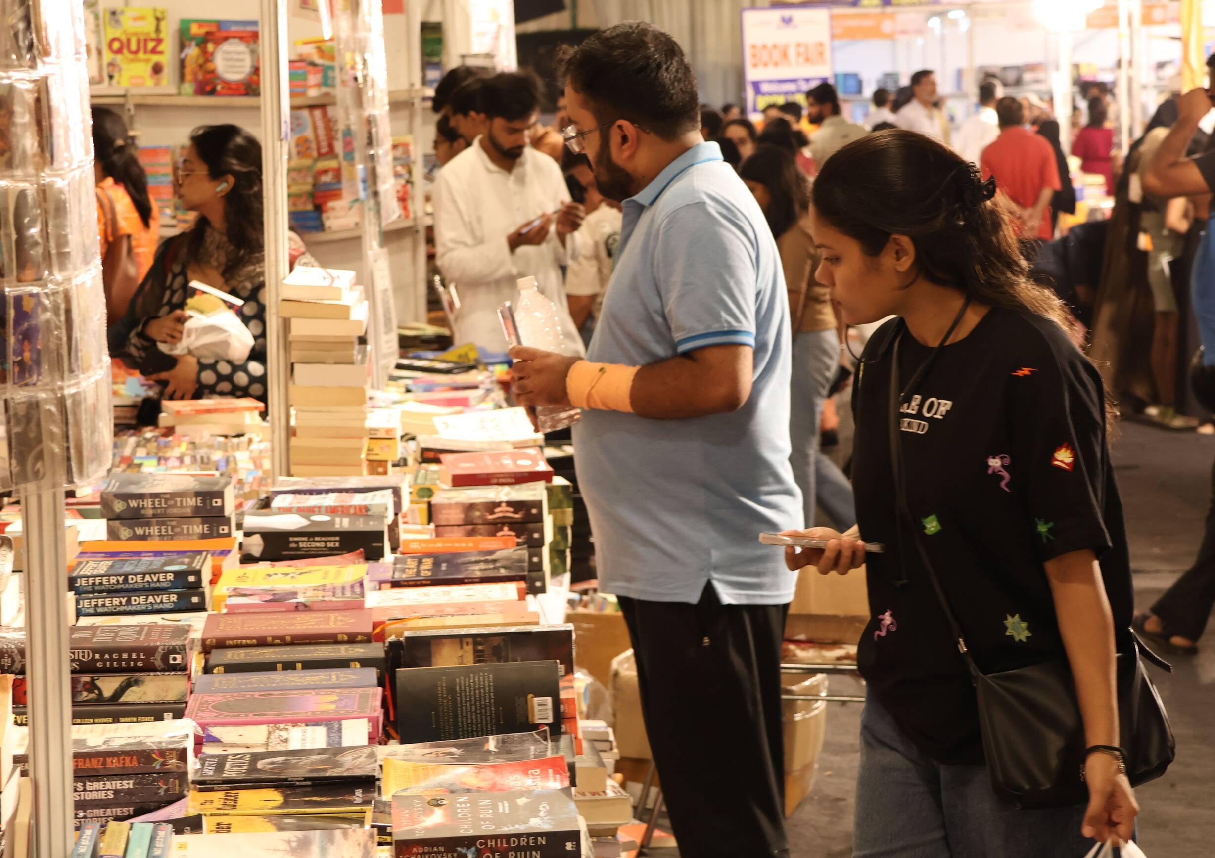 पुस्तक मेले में किताबें पसंद करते खरीदार। पुस्तक मेले में किताबें पसंद करते खरीदार।