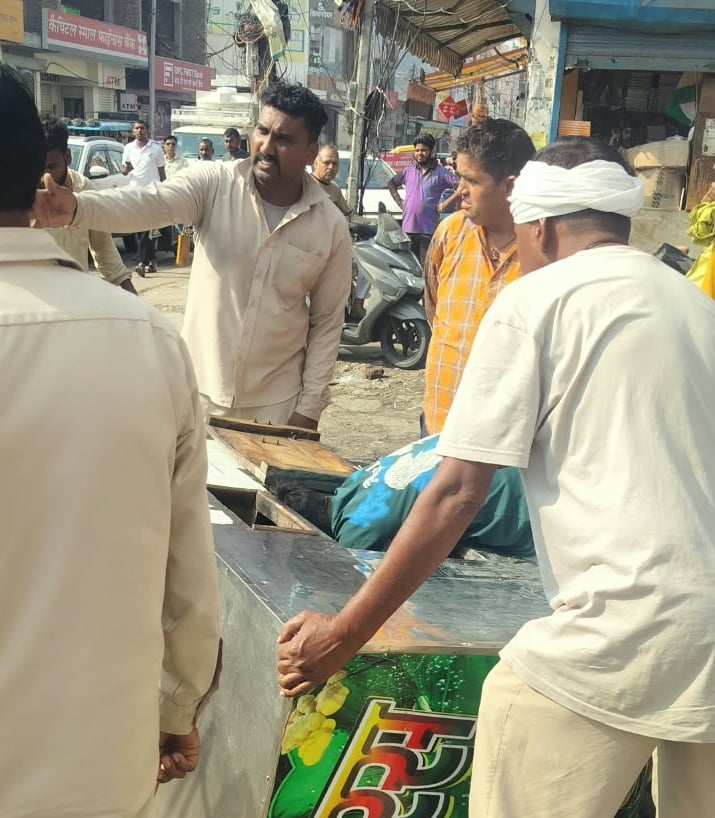 फोटो-53: मेन बाजार में सड़क पर रखे सामान को जब्त करते कर्मचारी। संवाद
