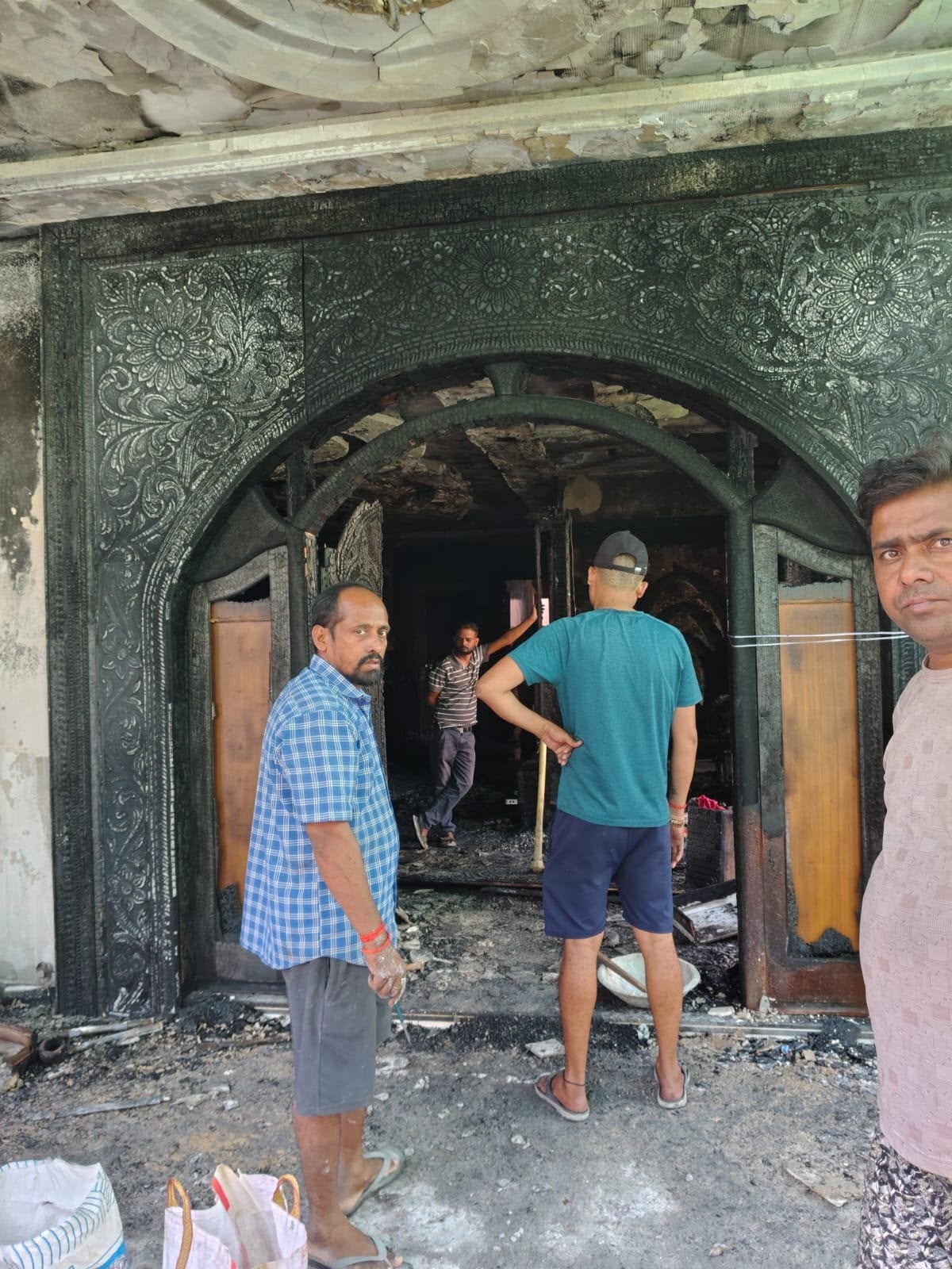 घर से निकलतीं आग की लपटें और आग बुझाते लोग। घर से निकलतीं आग की लपटें और आग बुझाते लोग।