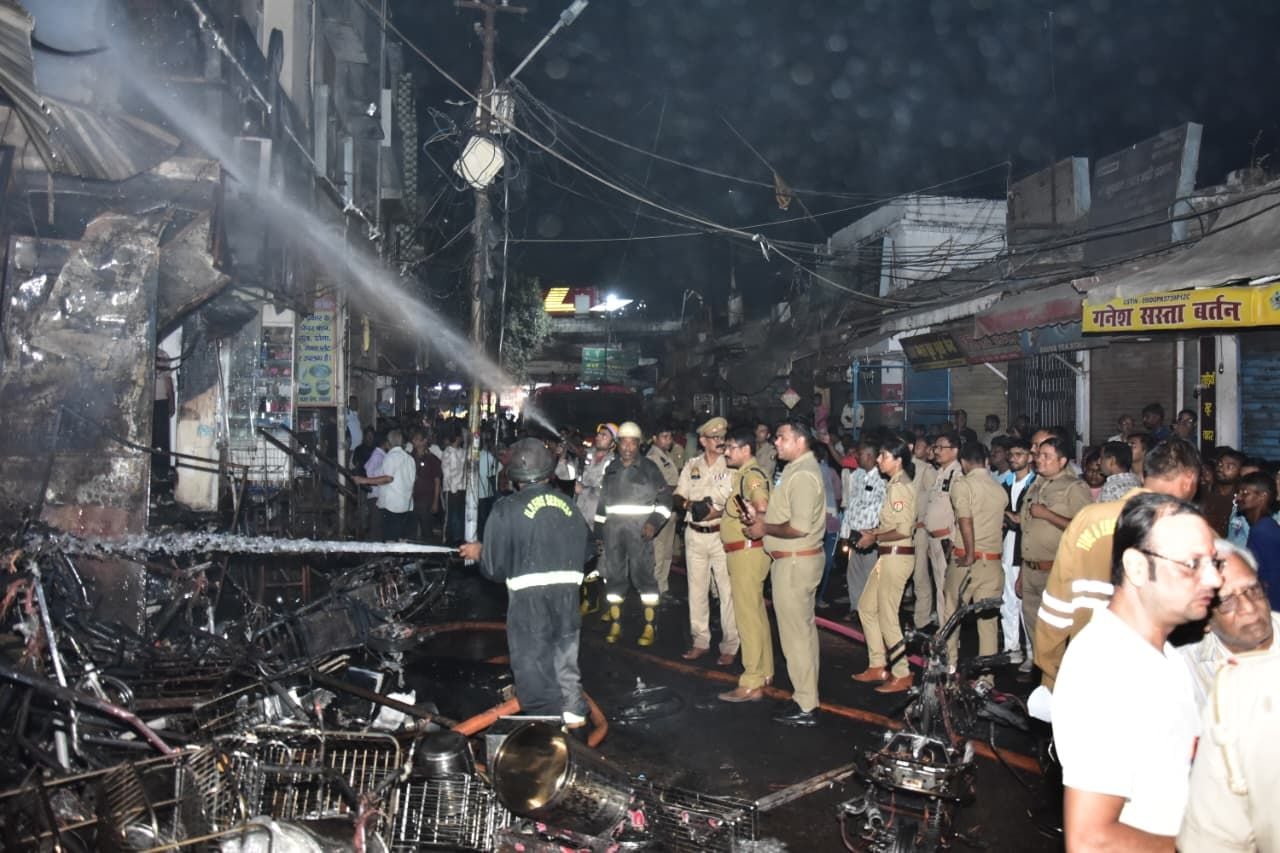 सदर बाजार स्थित ई स्कूटी शोरूम व बर्तन की दुकान से उठतीं लपटें व आग बुझाते दमकल कर्मी।