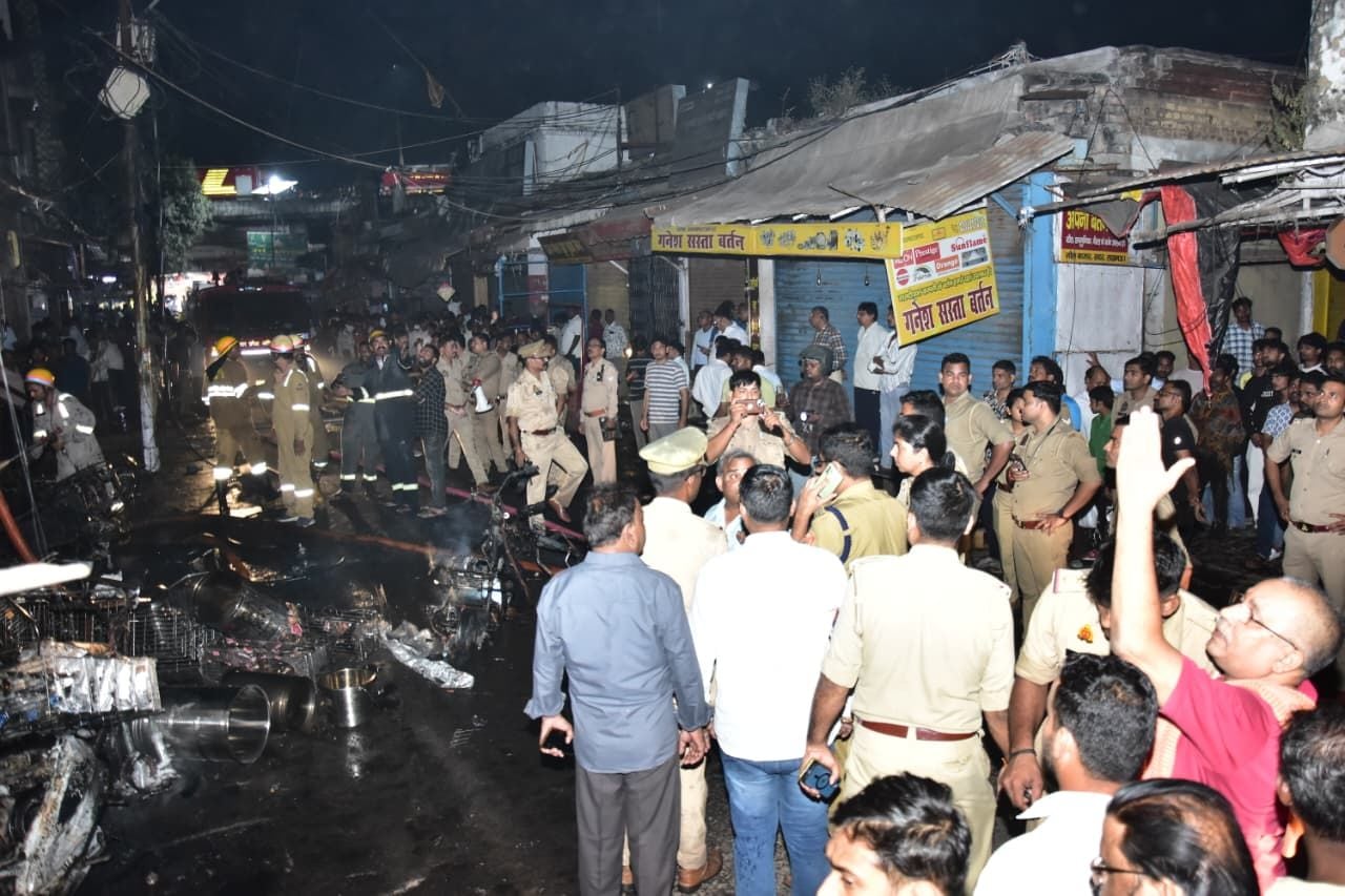सदर बाजार स्थित ई स्कूटी शोरूम व बर्तन की दुकान से उठतीं लपटें व आग बुझाते दमकल कर्मी।