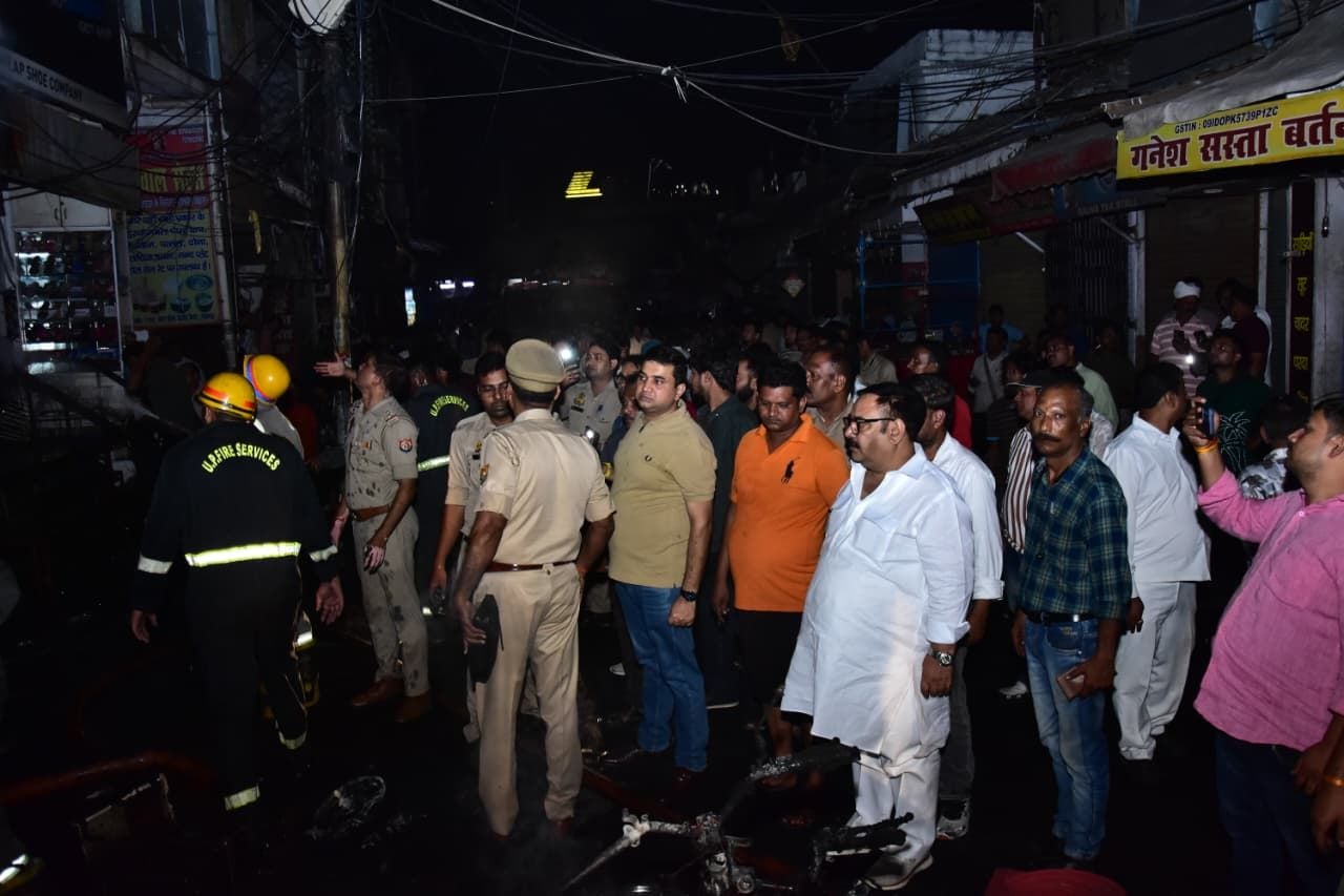 सदर बाजार स्थित ई स्कूटी शोरूम व बर्तन की दुकान से उठतीं लपटें व आग बुझाते दमकल कर्मी।
