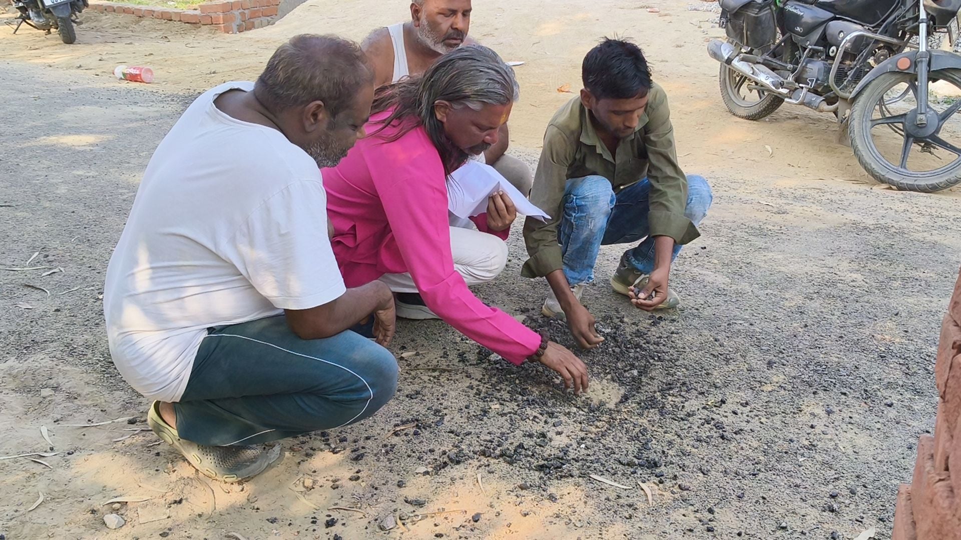प्रदर्शन करते और सड़क से उखड़ रहीं गिट्टियों को दिखाते ग्रामीण।