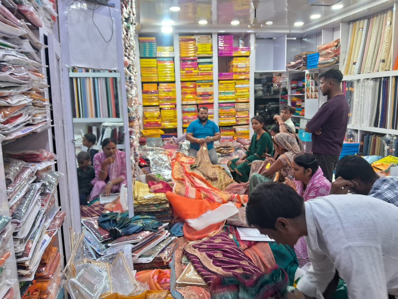 कपड़े की दुकान पर साड़ी खरीदती महिलाएं संवाद