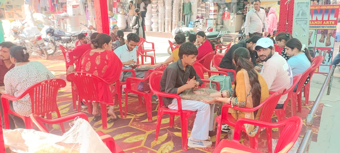 गुहला-चीका में करवा चौथ पर्व को लेकर सजे बाजार में हाथों पर मेहंदी लगवाती युवतियां। संवाद