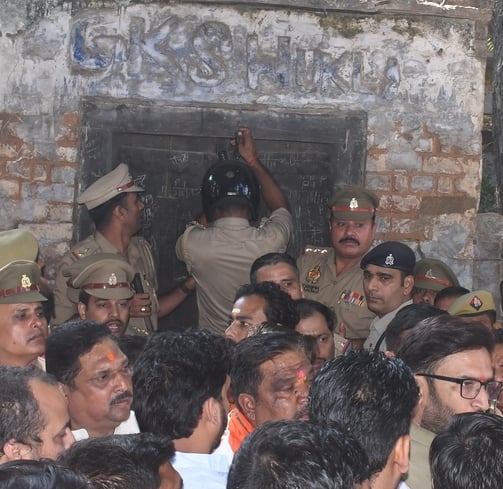 हत्या के आरोपी के घर में घुसे लोगों को निकालती पुलिस। हत्या के आरोपी के घर में घुसे लोगों को निकालती पुलिस।