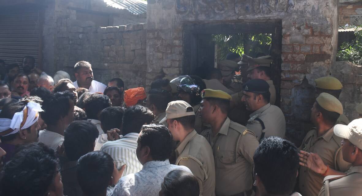 हत्या के आरोपी के घर में घुसे लोगों को निकालती पुलिस। हत्या के आरोपी के घर में घुसे लोगों को निकालती पुलिस।