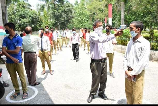 रुद्रपुर में परीक्षा से पूर्व छात्रों की थर्मल स्क्रीनिंग करते शिक्षक।