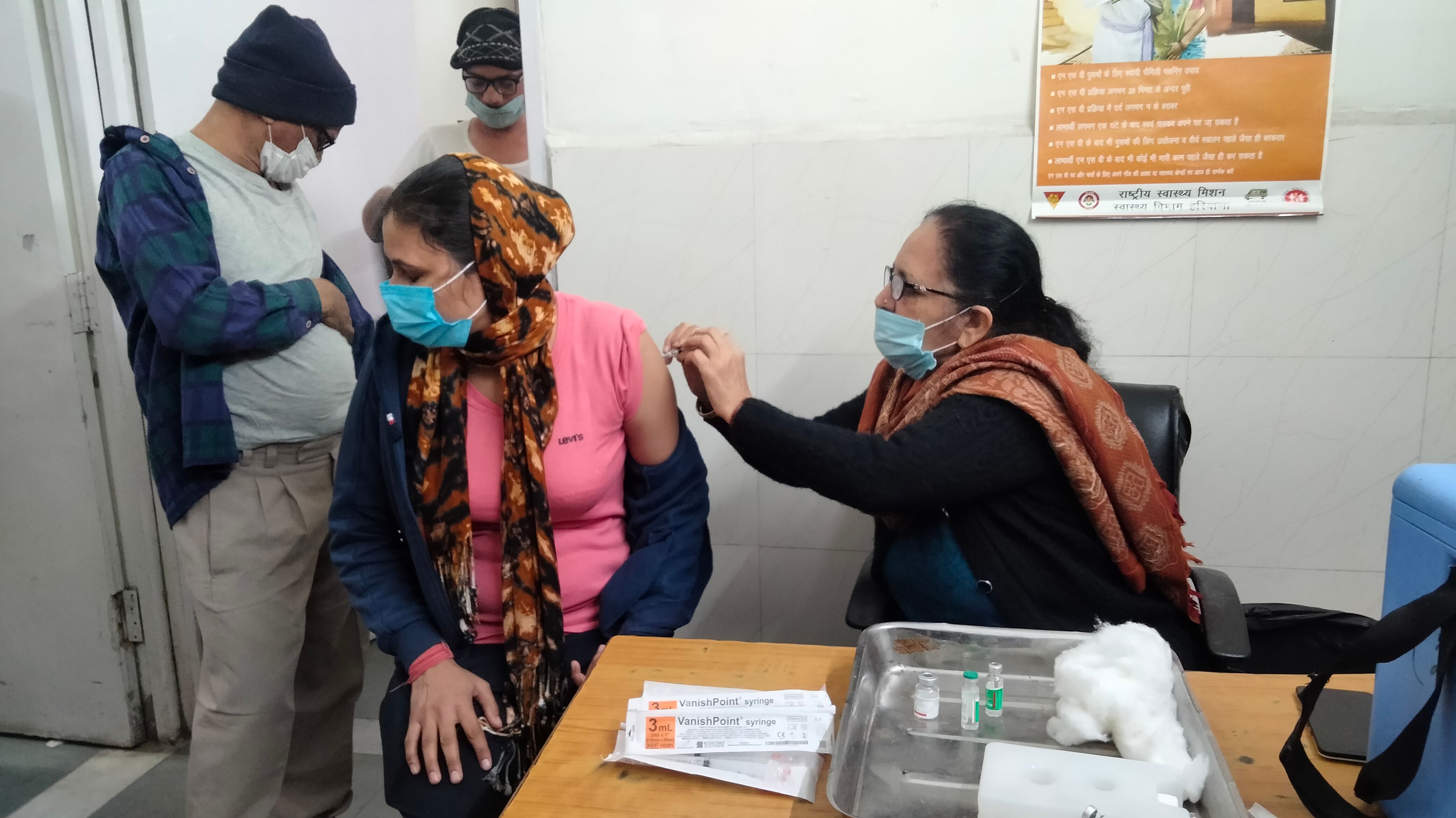 Wanita mendapatkan vaksin di rumah sakit kabupaten.  percakapan